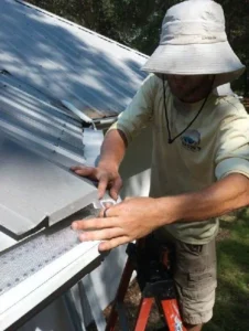 Rain Storm Solutions tech installing gutters on a metal roof